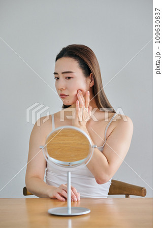 鏡を見ながら肌のシワを気にする30代女性 鏡を見ながら肌のシワを気にする30代女性 109630837