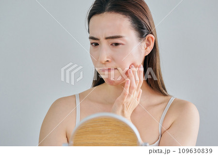 鏡を見ながら肌のシワを気にする30代女性 鏡を見ながら肌のシワを気にする30代女性 109630839