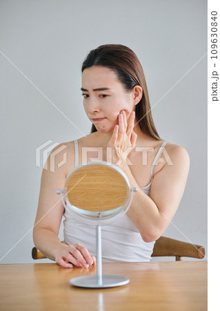 鏡を見ながら肌のシワを気にする30代女性 鏡を見ながら肌のシワを気にする30代女性 109630840