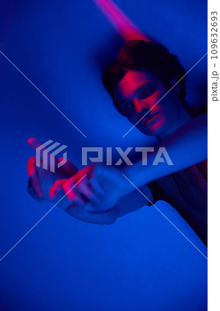 Young guy posing against dark blue background in neon light. Attractive youth. Night club 109632693