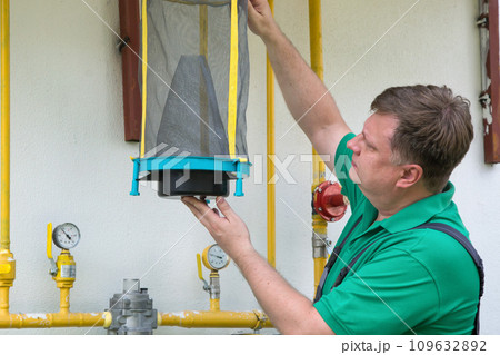 A man hangs a reusable trap for flies and muskies near his house A man hangs a reusable trap for flies and muskies near his house 109632892