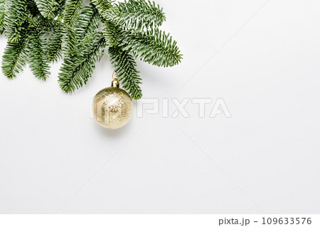 Merry Christmas and Happy New Year. Christmas evergreen spruce noble fir tree and golden ball on festive white background. Copy space. Greeting card Merry Christmas and Happy New Year. Christmas evergreen spruce noble fir tree and golden ball on festive white background. Copy space. Greeting card 109633576