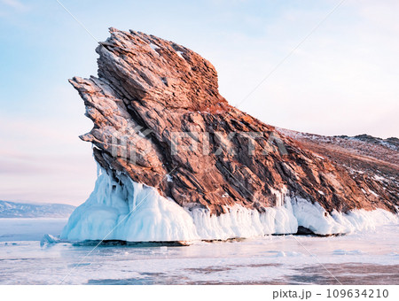 Ogoy island on winter Baikal lake. Winter scenery of Dragon Tail Rock on Ogoy island during sunrise at Lake Baikal. 109634210