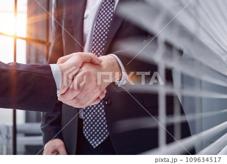 executives shaking hands in front of their manager and a colleague 109634517