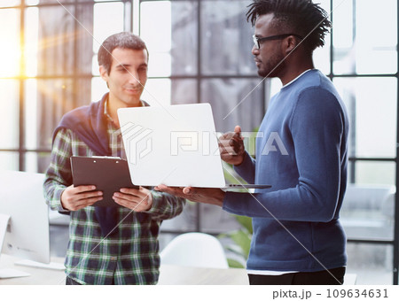 young business men standing together holding a laptop, discussing business young business men standing together holding a laptop, discussing business 109634631