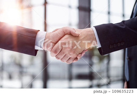 executives shaking hands in front of their manager and a colleague 109635223