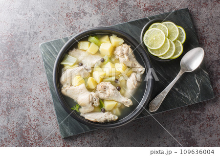 Chicken souse is a Bahamian soup consisting of clear broth where the meat and the vegetables are boiled down in the juice of fresh citrus closeup on the plate. Horizontal top view 109636004