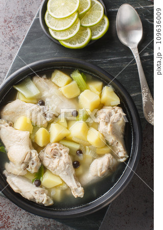 Bahamian chicken souse is a poultry dish made with chicken wings, onions, potatoes, celery, lime juice, allspice closeup on the plate on the table. Vertical top view Bahamian chicken souse is a poultry dish made with chicken wings, onions, potatoes, celery, lime juice, allspice closeup on the plate on the table. Vertical top view 109636009