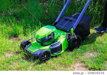Mowing green grass using an electric lawn mower is gardener man Mowing green grass using an electric lawn mower is gardener man 109638338