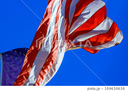 An American flag waving in wind against blue sky 109638638