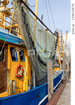 Colorful traditional old german fishing cutter boats moored Neuharlingersiel harbor Wadden sea East Frisia Northern Germany. Commercial fish crab shrimp trawler trawl nets North Sea small port city 109639676