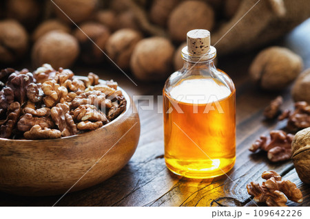 Walnuts in a wooden crate on wooden table. Walnuts in basket and nuts oil on  table Bottles of essential nut oil. 109642226