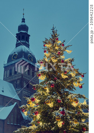 Decorated Christmas tree at the Dome Square in old Riga city, Riga Cathedral tower on background. Riga, Latvia. Decorated Christmas tree at the Dome Square in old Riga city, Riga Cathedral tower on background. Riga, Latvia. 109642228