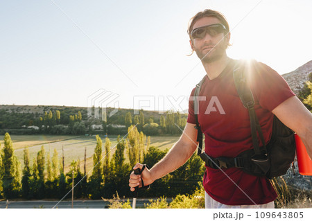 Young man hiker travels through the mountains with trekking poles for nordic walking 109643805
