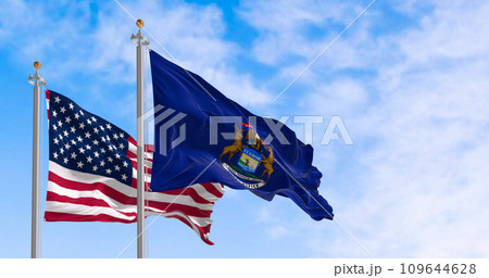 Michigan state flag and national american flag waving in the wind on a clear day 109644628