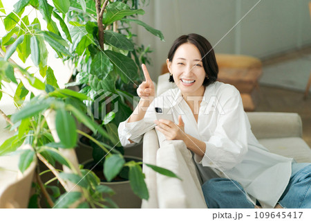 ソファでスマホを操作するミドル女性 109645417