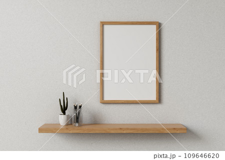 Front view of a minimalist wooden picture frame on a white wall in a minimal, Scandinavian room. Front view of a minimalist wooden picture frame on a white wall in a minimal, Scandinavian room. 109646620