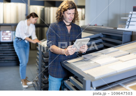 in construction department,man chooses facing plates for apartment repairs. in construction department,man chooses facing plates for apartment repairs. 109647503