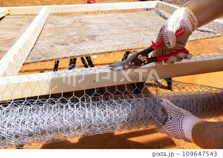 Worker uses scissors for metal to cut metal mesh Worker uses scissors for metal to cut metal mesh 109647543