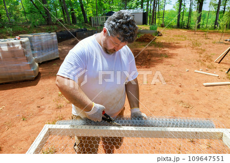 An employee is using scissors metal to cut metal mesh 109647551