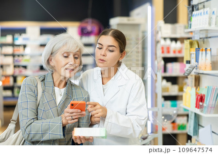 Old woman showing to young female pharmacist QR-code of product on her smartphone 109647574