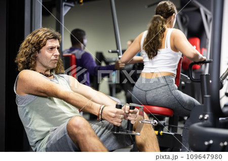 Caucasian man doing exercises on cable row machine in gym 109647980