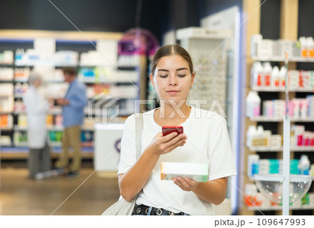 Young girl customer scanning QR of medical product held in hand in chemist's shop 109647993