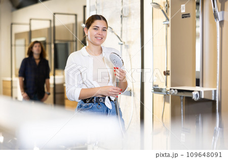 in plumbing department,woman examines shower head and quality of metal coating. 109648091