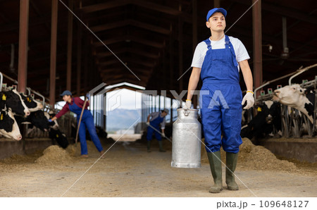 Young boy farmer with can works on dairy farm 109648127
