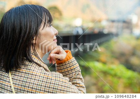 紅葉の中たたずむ女性 109648284