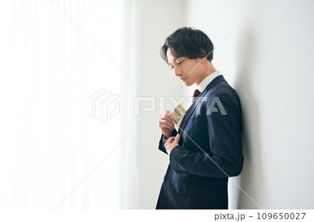 札束をポケットにしまう男性 札束をポケットにしまう男性 109650027
