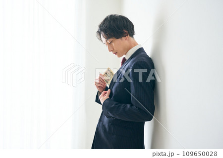 札束をポケットにしまう男性 札束をポケットにしまう男性 109650028