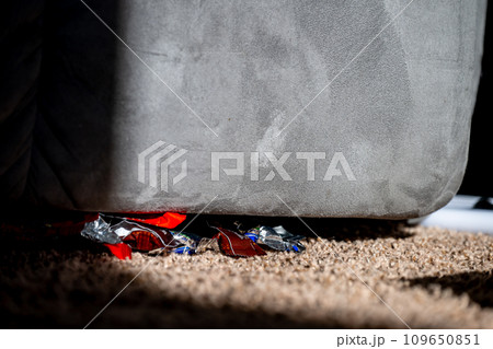Hidden candy wrappers under a chair in the corner. 109650851