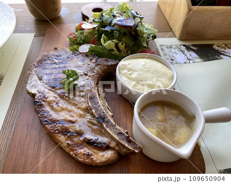 Grilled or fried pork chops on the bone with salad and mashed potatoes served on wooden board 109650904