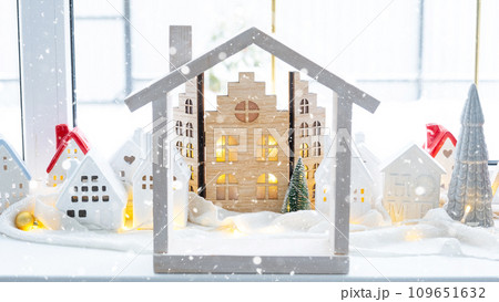 Cozy Christmas decor tiny house of small size on window sill with snow outside the window. Gift for New Year. Insurance, moving to new house, mortgage, rent and purchase real estate 109651632