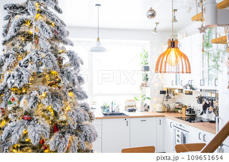 Festive Christmas decor in white kitchen, modern rustic interior with a snowy Christmas tree and fairy lights. New Year, Christmas mood, cozy home. The general plan 109651654