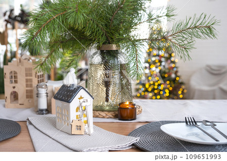 Key and tiny house of a small size on cozy home with Christmas decor on table of festive kitchen. Gift for New Year. Insurance, moving to new house, mortgage, rent and purchase real estate 109651993