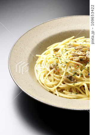 沢山のアサリと赤唐辛子、イタリアンパセリ、ガーリックチップの乗ったボンゴレビアンコを黒背景で撮影 109653422