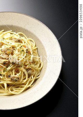 沢山のアサリと赤唐辛子、イタリアンパセリ、ガーリックチップの乗ったボンゴレビアンコを黒背景で俯瞰撮影 109653498