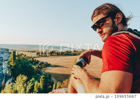 Hiker man with backpack holding thermos in his hand 109655667