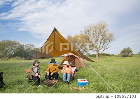 キャンプを楽しむ若い男女・焚き火をするアウトドアイメージ 109657101