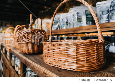 Wicker Baskets on Rustic Wooden Shelves. Assorted wicker baskets displayed on wooden shelving in a cozy, rustic Organic Food shop setting. 109660715