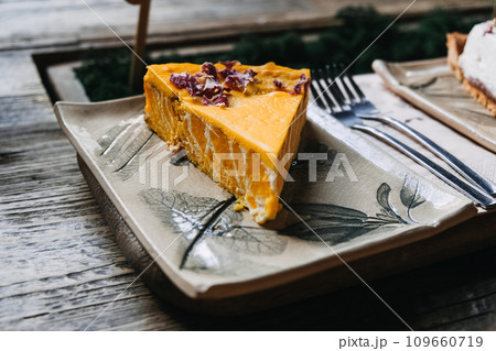 Pumpkin Pie Slice with rose petals on Decorative Ceramic Plate. A delicious slice of pumpkin pie topped with garnish, served on a botanical-themed ceramic plate. 109660719