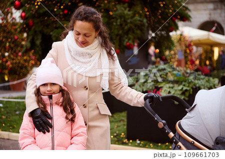 Mother and daughter walking together at Christmas fair. Festive atmosphere in December in Italy. People and holidays 109661703