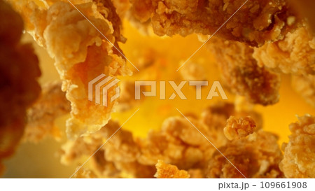 Freeze motion of flying pieces of fried chicken pieces on colored background. 109661908