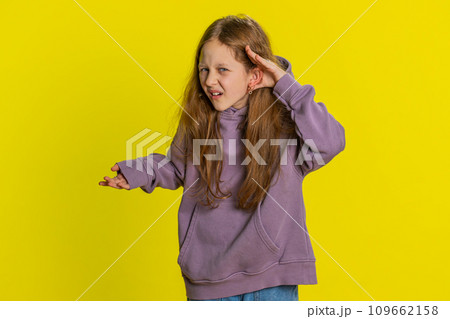 Child girl kid trying hear you looking confused and frowning, keeping arm near ear for louder voice 109662158
