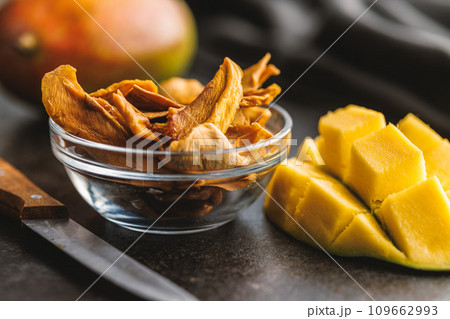 Dried mango fruit in bowl on black table. 109662993