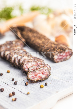 Smoked dried sausage. Sliced sausage on cutting board. 109663055