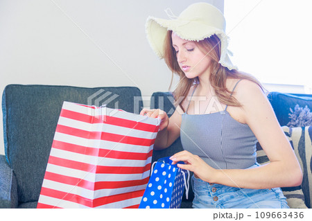 リビングルームでショッピングバックをあける外国人 リビングルームでショッピングバックをあける外国人 109663436