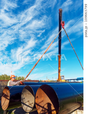 New pipes for gasification. Worker in construction helmet ships large-diameter metal pipes New pipes for gasification. Worker in construction helmet ships large-diameter metal pipes 109663799